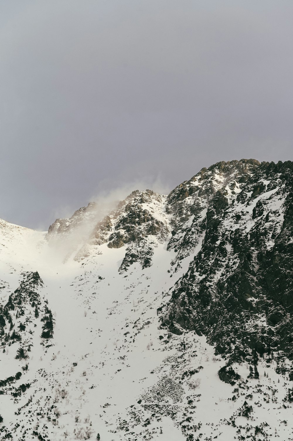 Ein schneebedeckter Berg mit einer Wolke am Himmel