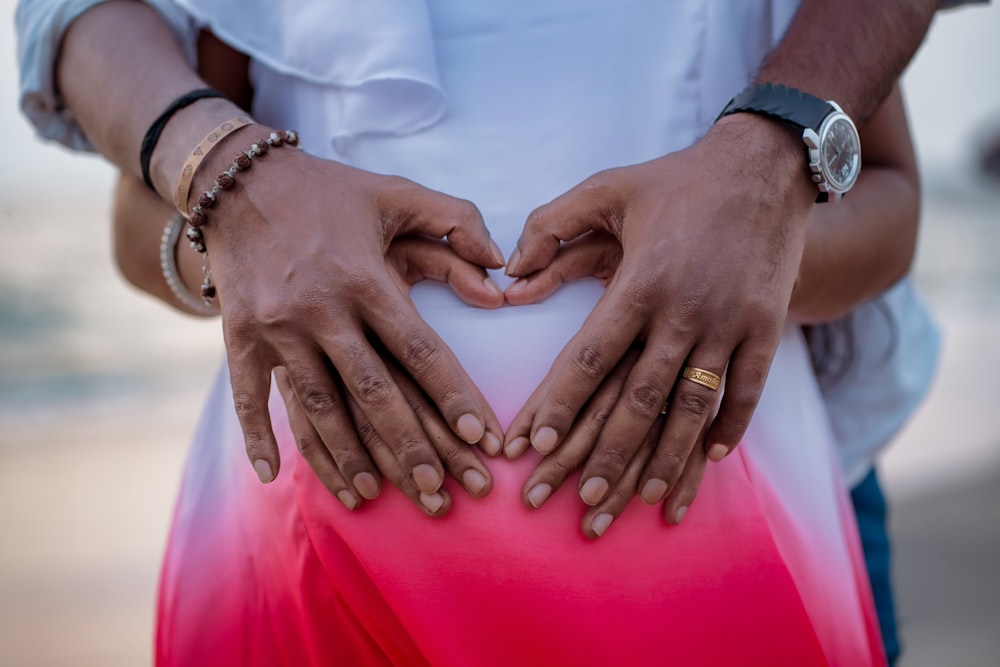 a man and a woman holding hands in the shape of a heart