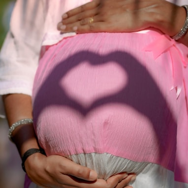 a pregnant woman holding her belly with a heart shaped shadow on it