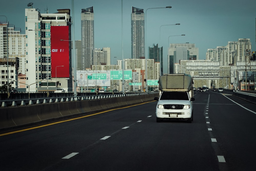 a white car driving down a highway next to tall buildings