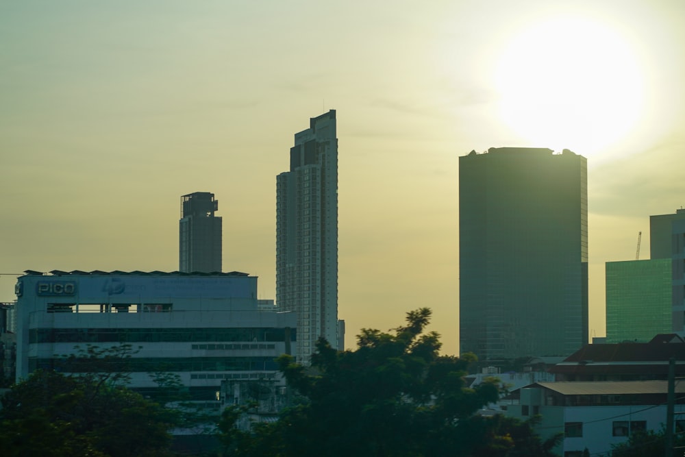 the sun is setting over a city with tall buildings