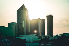 A modern cityscape featuring government buildings with reflective glass facades during sunset.