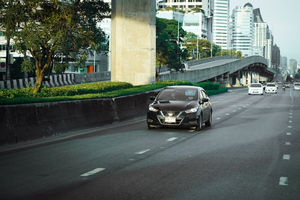 a black car driving down a street next to tall buildings