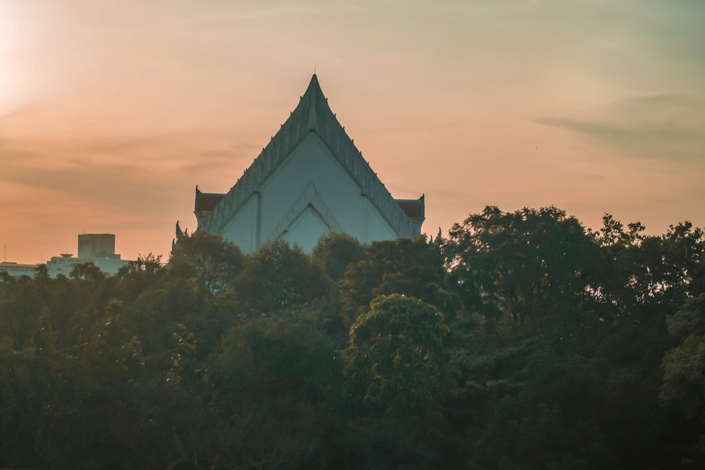 a building with a triangle shaped roof surrounded by trees