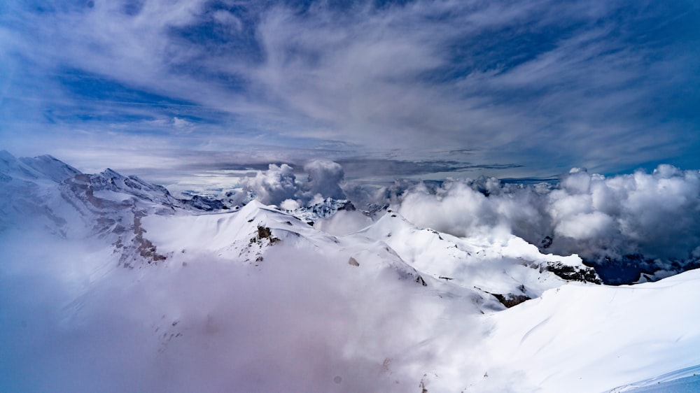 a snowy mountain with clouds in the sky