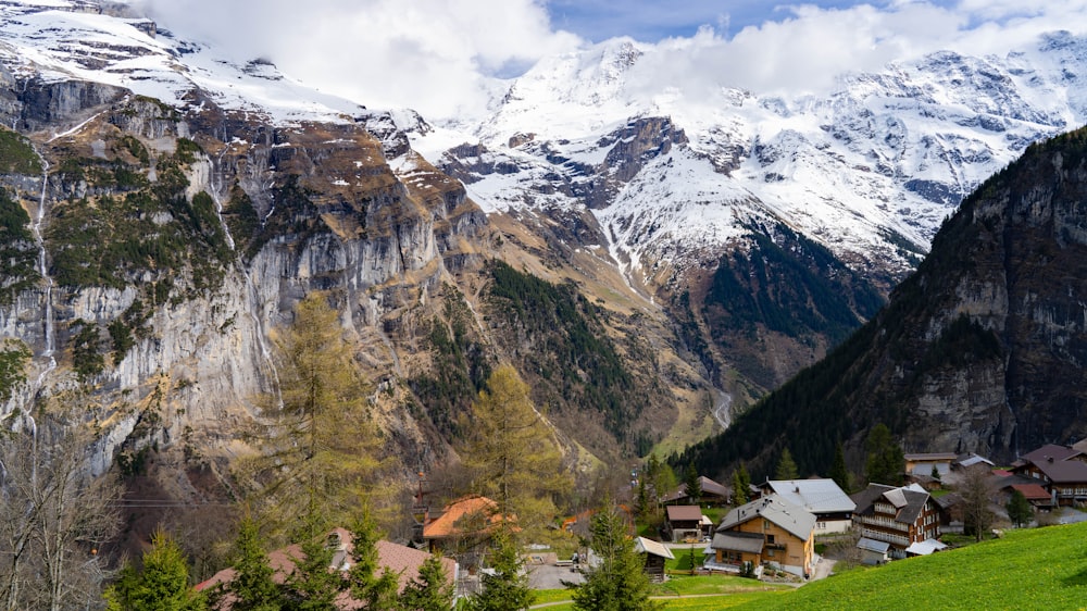 a scenic view of a mountain village with a snow - capped mountain in the background