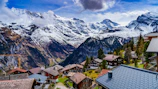 A charming alpine village nestled among vibrant green hills under a clear blue sky.