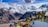 Charming alpine village nestled in a lush valley with snow-capped mountains in the background. Traditional wooden houses with sloped roofs are scattered throughout the scene, surrounded by evergreens and vibrant green grass. A clear blue sky with scattered clouds hangs above the majestic peaks.