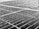 Close-up of a solar panel surface covered in numerous raindrops. The texture is visible, with droplets of varying sizes reflecting light. The panel is composed of multiple cells with visible grid lines that create a geometric pattern across the surface.