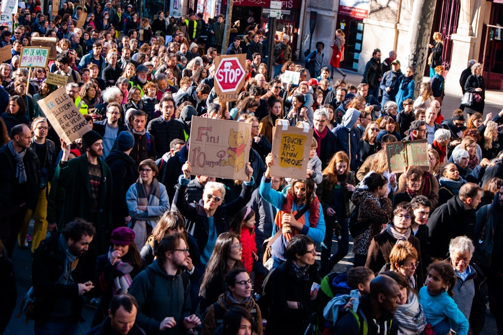 a crowd of people walking down a street holding signs