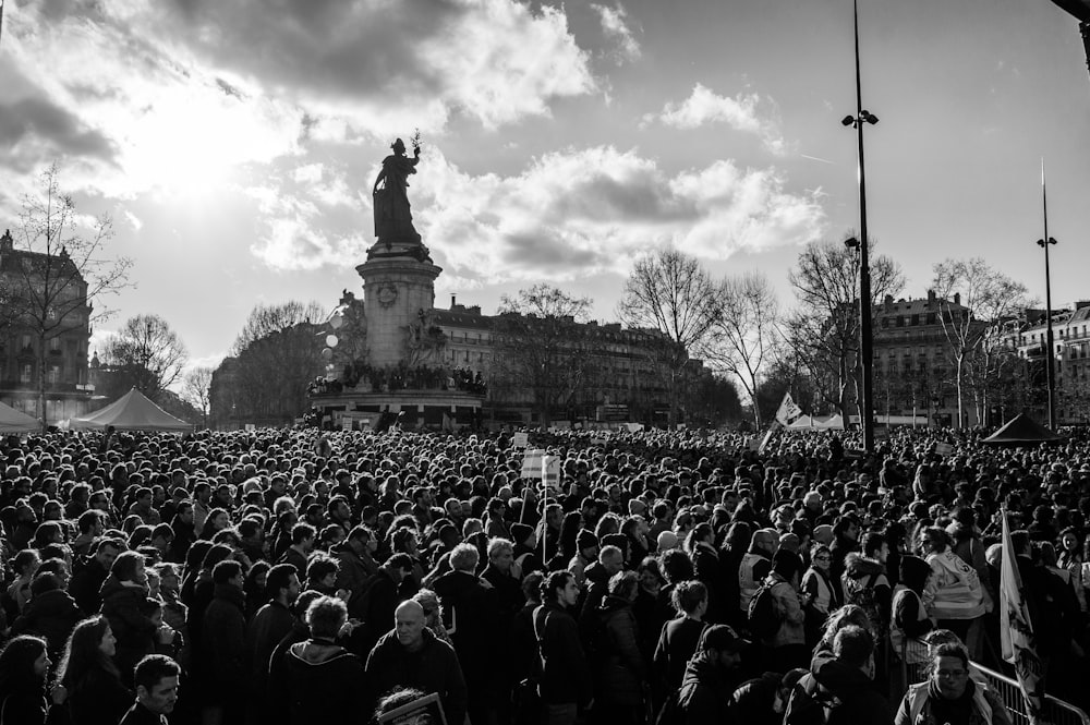 a large crowd of people standing in front of a statue