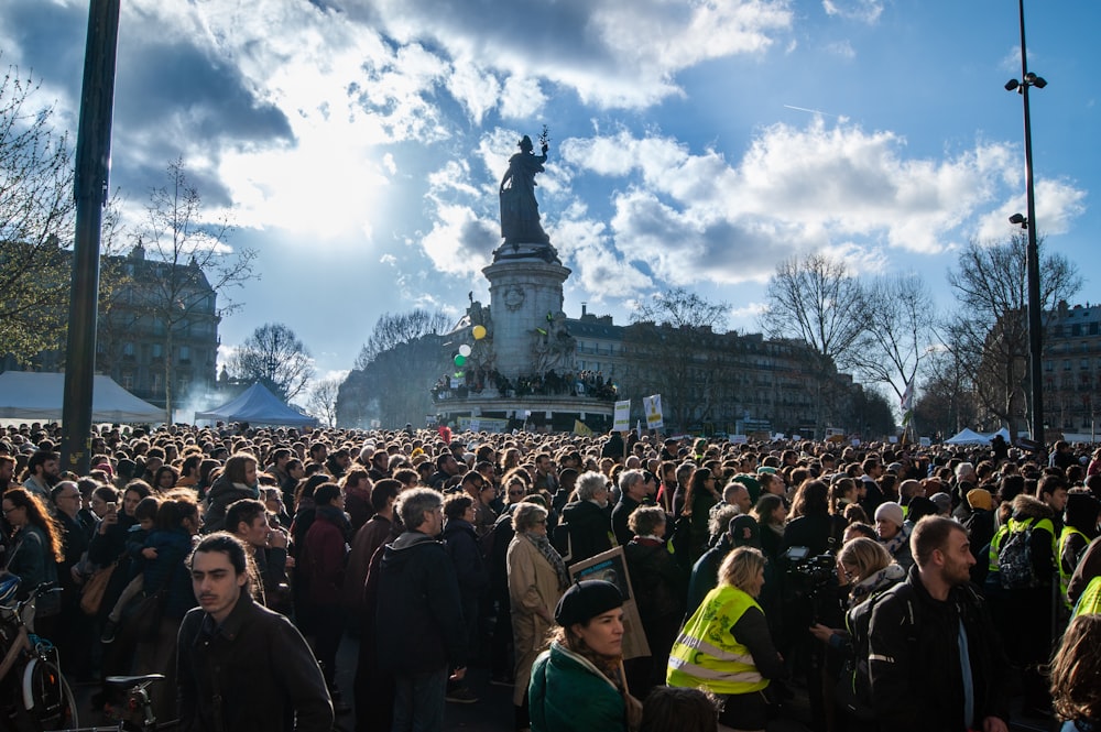 a large crowd of people standing in front of a statue