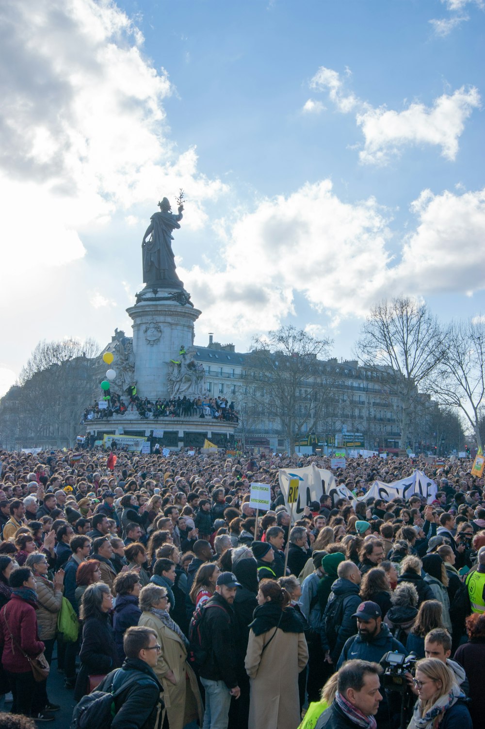 a large crowd of people standing in front of a statue