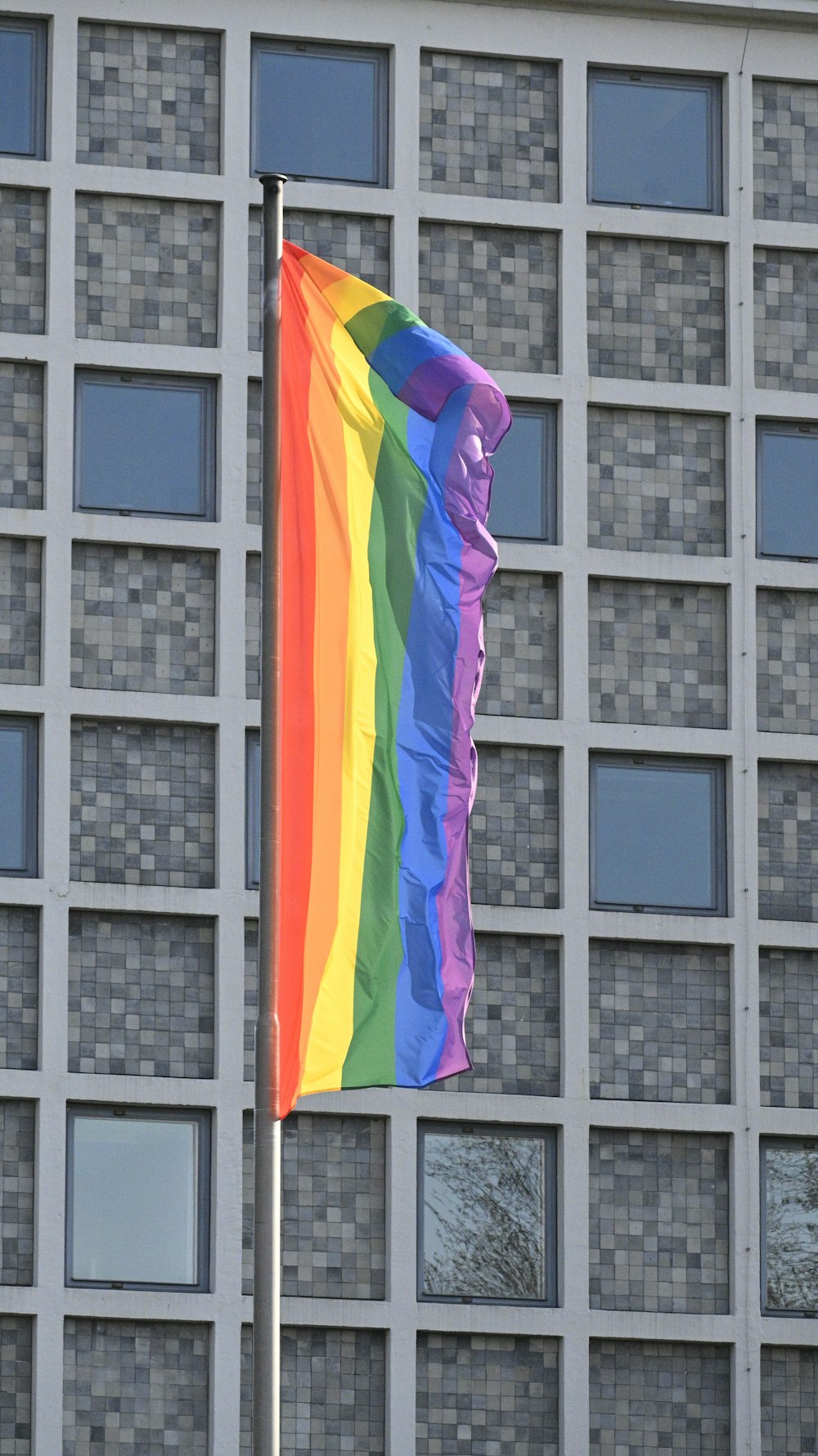 a rainbow flag flying in front of a building