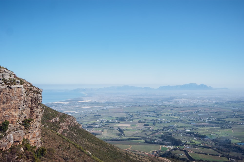 a man standing on top of a mountain next to a lush green valley