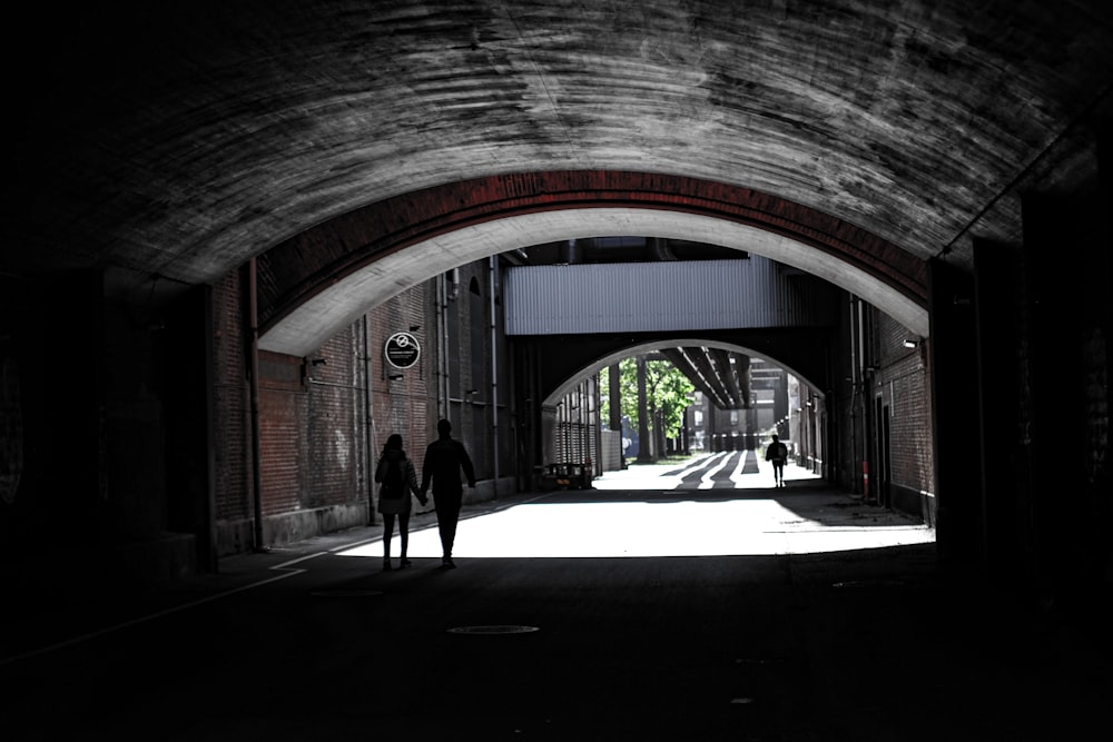 a couple of people that are walking under a bridge