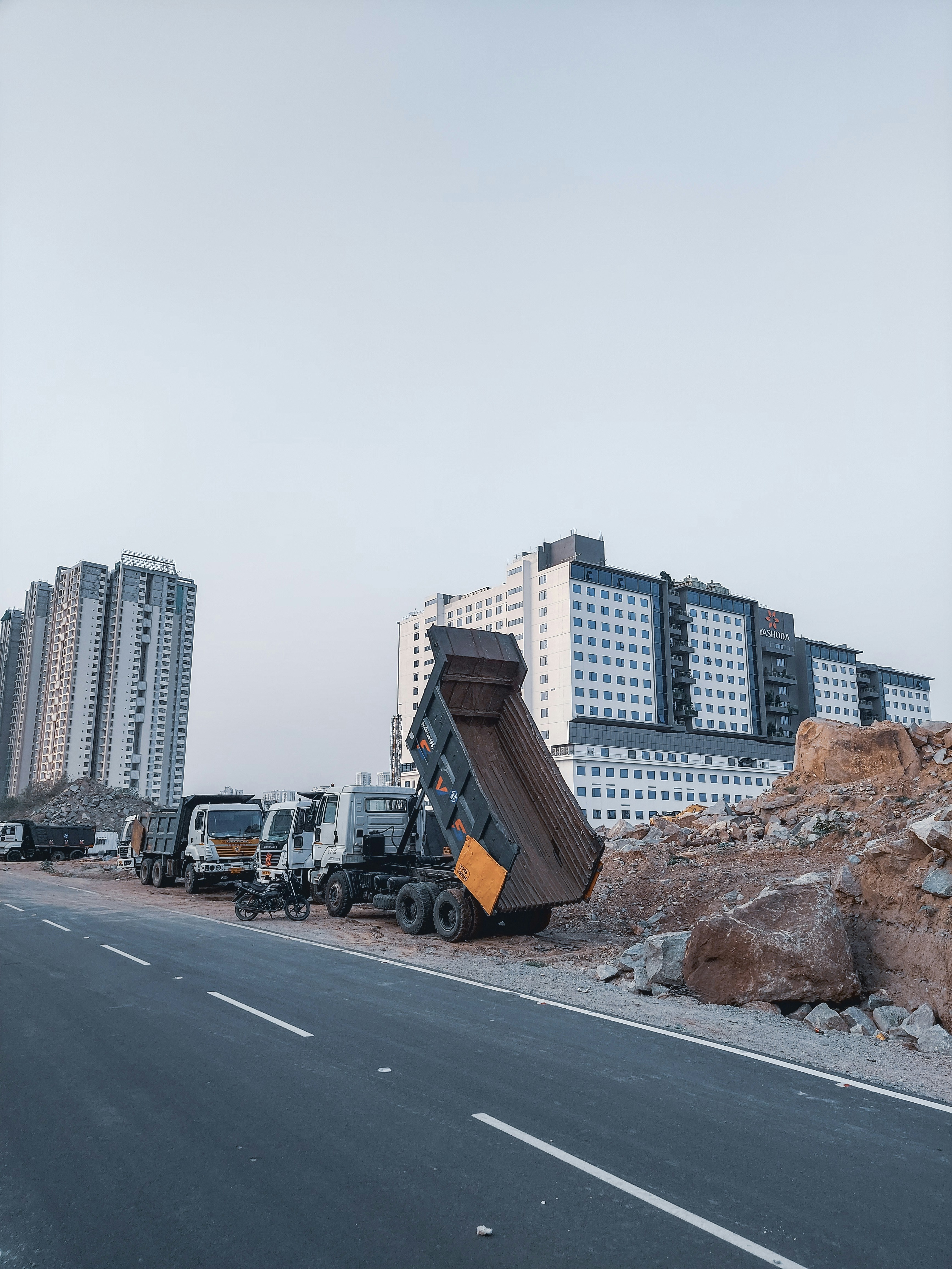 Blue tipper truck with raised bed dumping earth at construction site