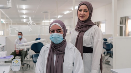 two women in hijabs standing in a dental office