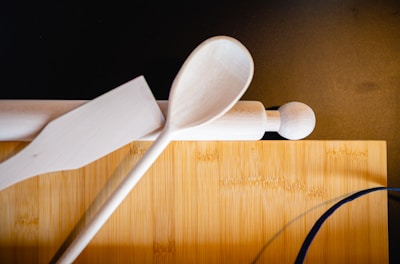 Close-up of elegant kitchen tools like spatulas and measuring cups resting on a wooden cutting board.