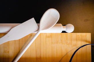 Close-up of kitchen supplies including spatulas, knives, and cutting boards on a wooden countertop.