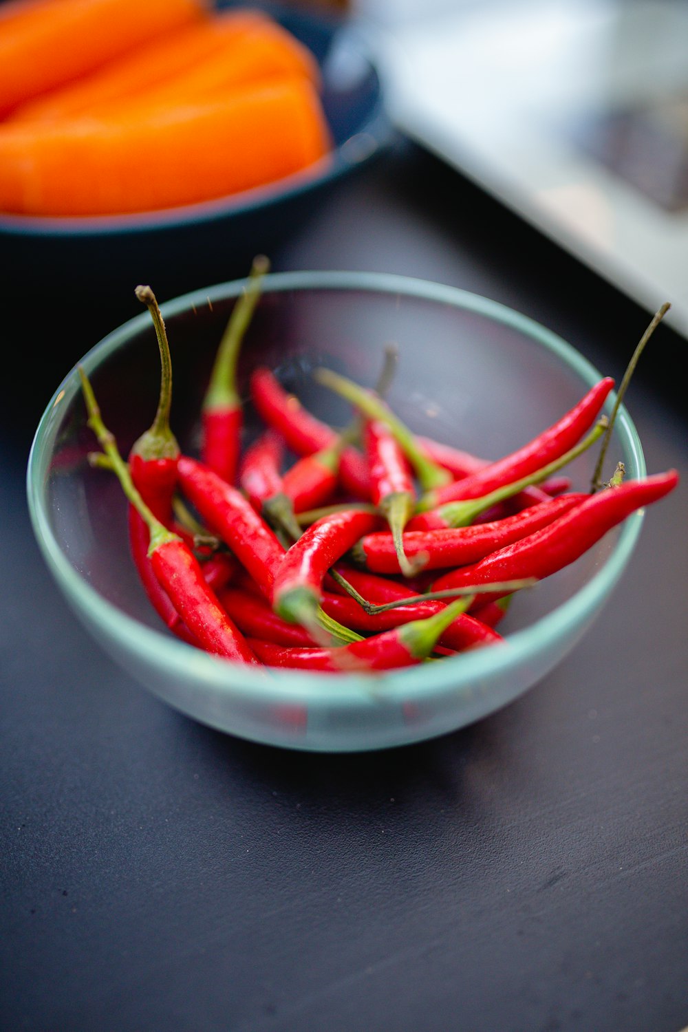 a bowl of red peppers and carrots on a table