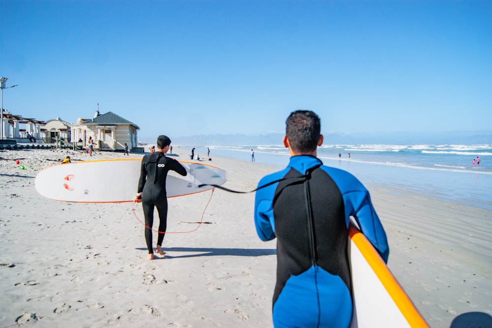 a man holding a surfboard while standing next to another man