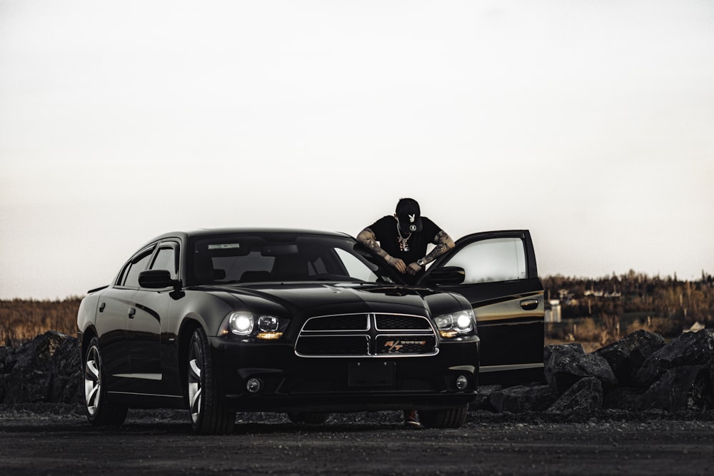 a man sitting on the hood of a black car