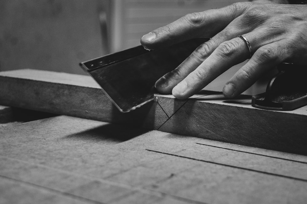 a person's hand on top of a piece of wood