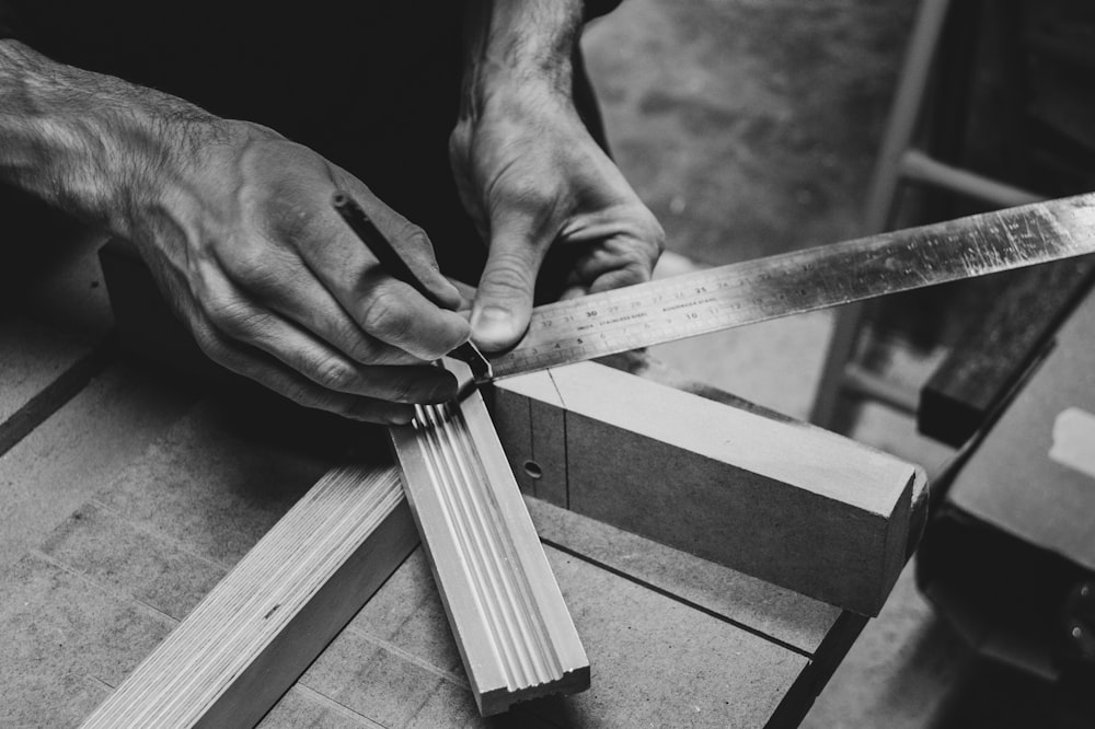 Una persona cortando un trozo de madera con un par de tijeras