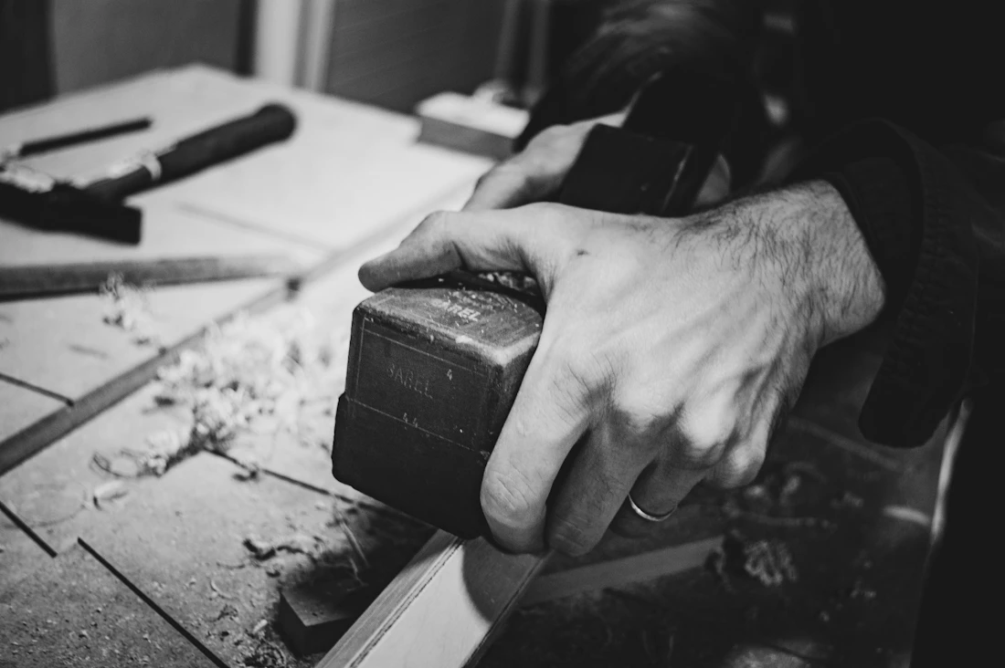 Craftsman's hands shaping a block on a workbench