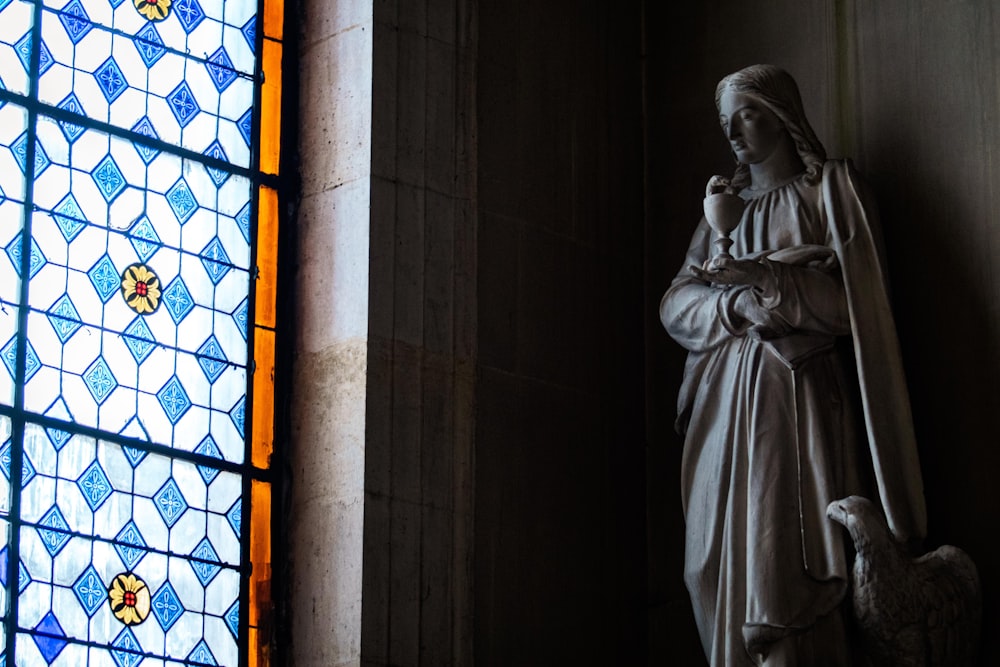 a statue next to a stained glass window