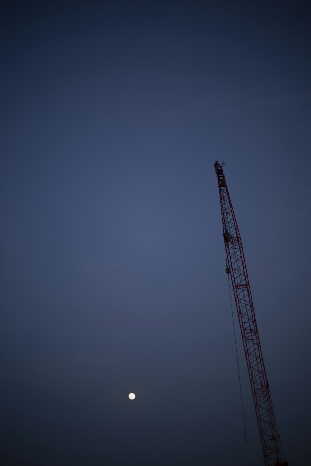 the moon is setting behind a crane in the sky