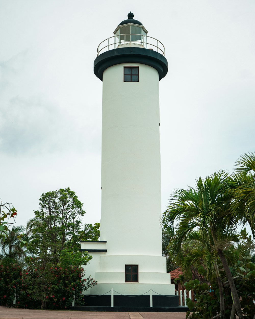 a white and black light house surrounded by trees