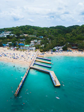 a long pier extending into the ocean next to a sandy beach