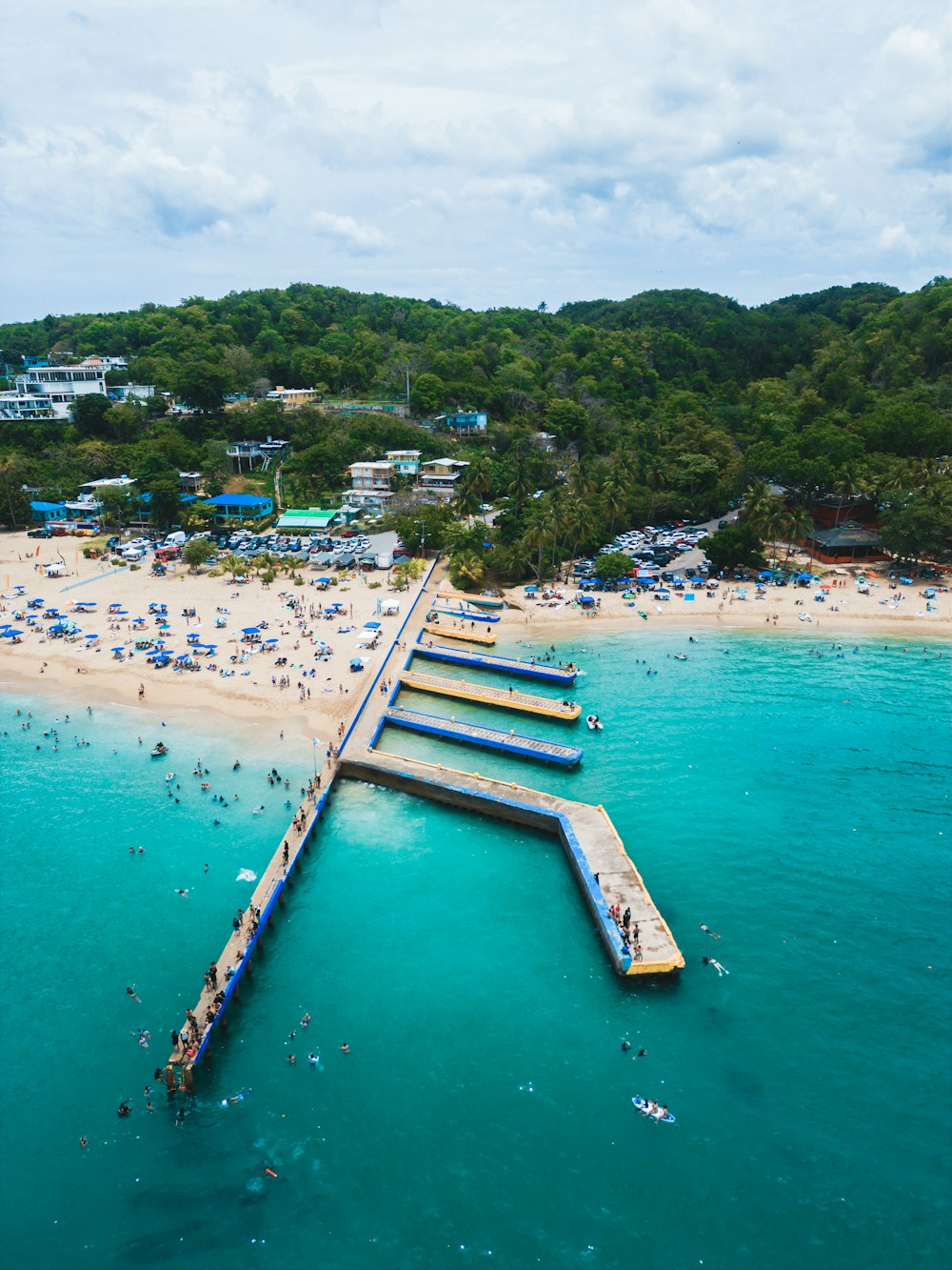 a long pier extending into the ocean next to a sandy beach