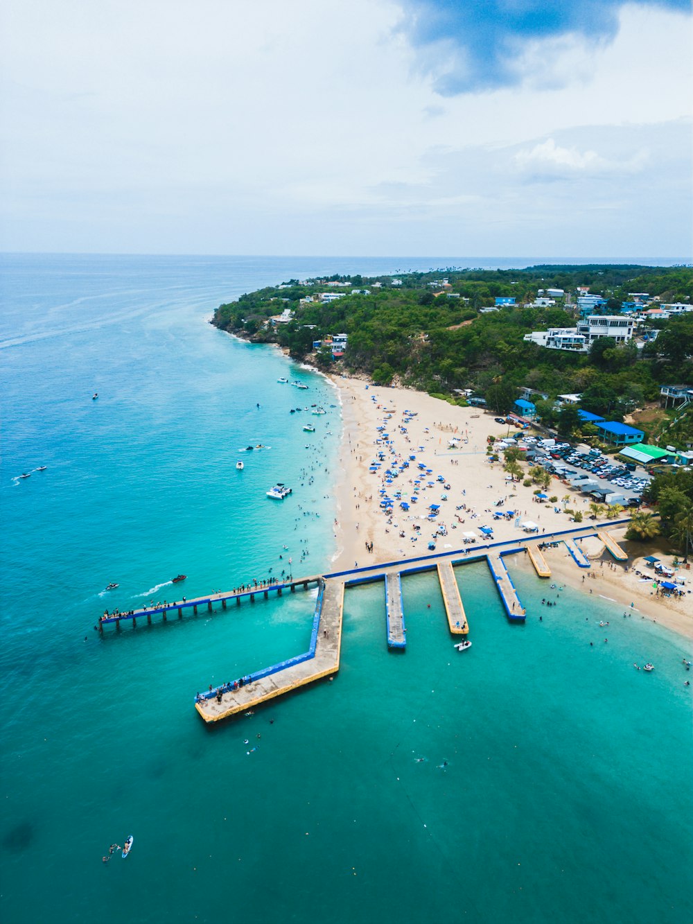 an aerial view of a beach with a pier and boats