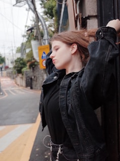 A person standing contemplatively in an urban environment with contrasting natural and industrial elements.