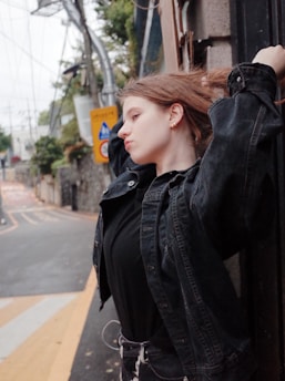 A person standing contemplatively in an urban environment with contrasting natural and industrial elements.