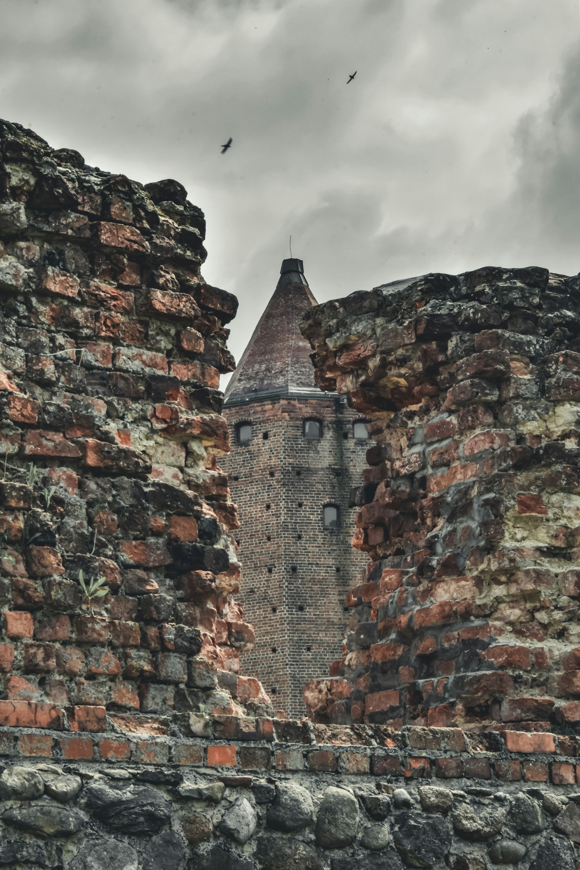an old brick wall with a clock tower in the background