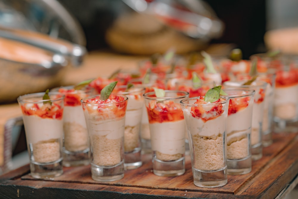 a wooden tray topped with glasses filled with food