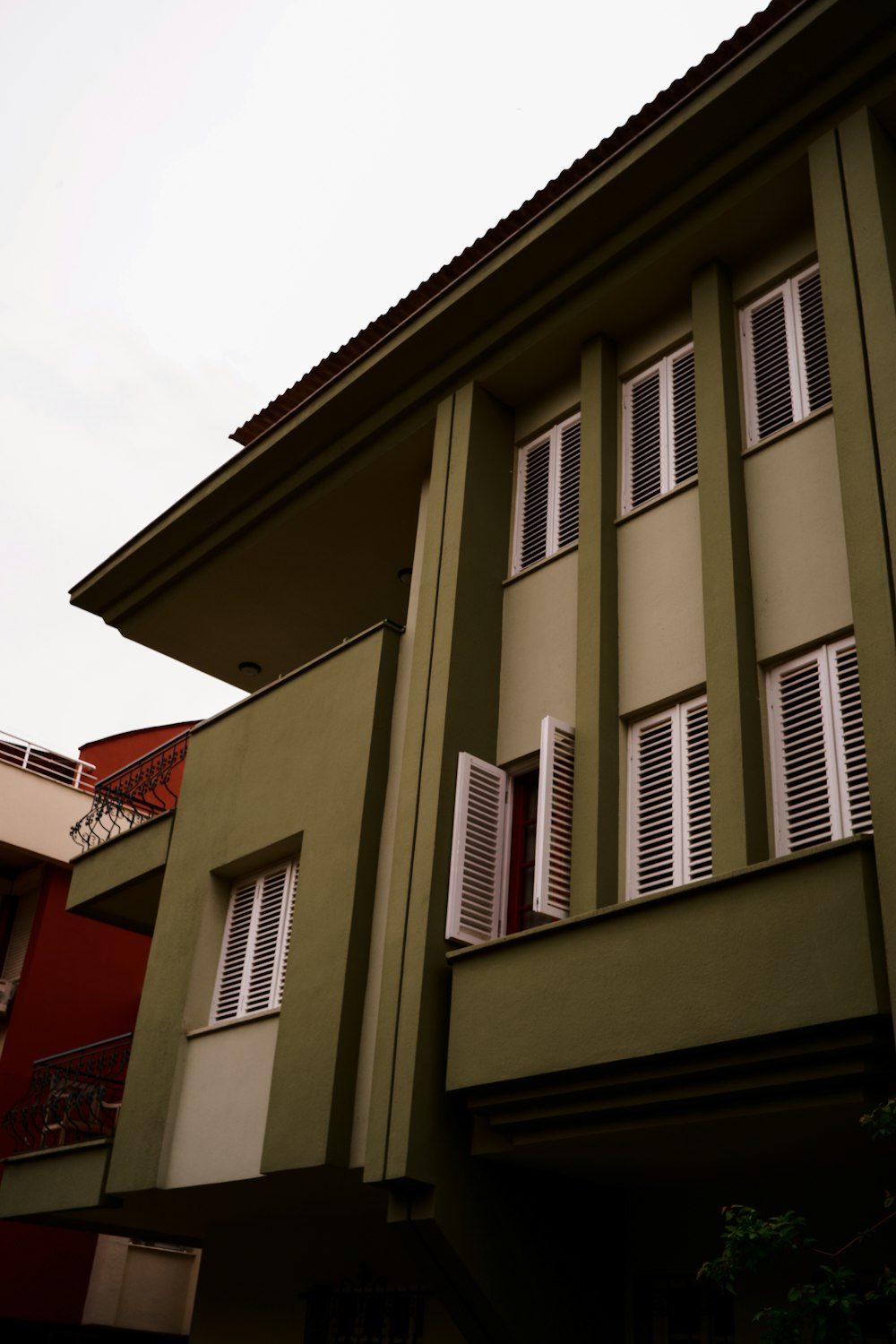 a green building with white shutters and a balcony