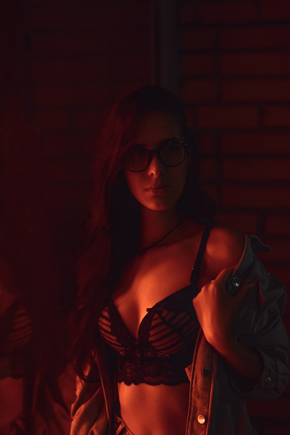 a woman in a bra and jacket standing in a dark room
