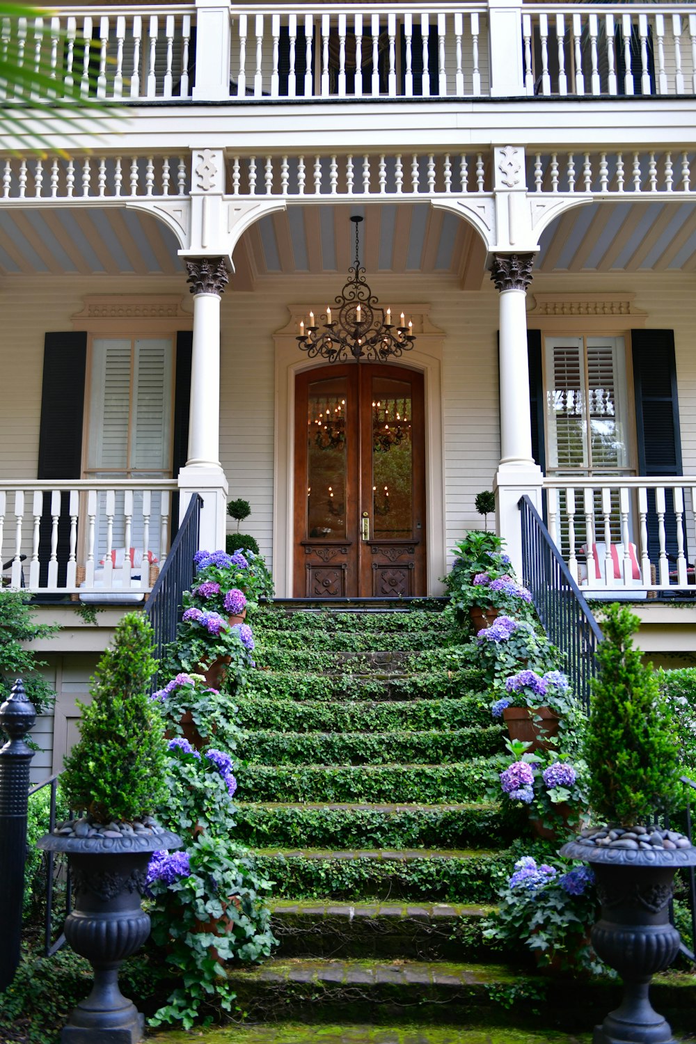 a large white house with a bunch of flowers on the steps