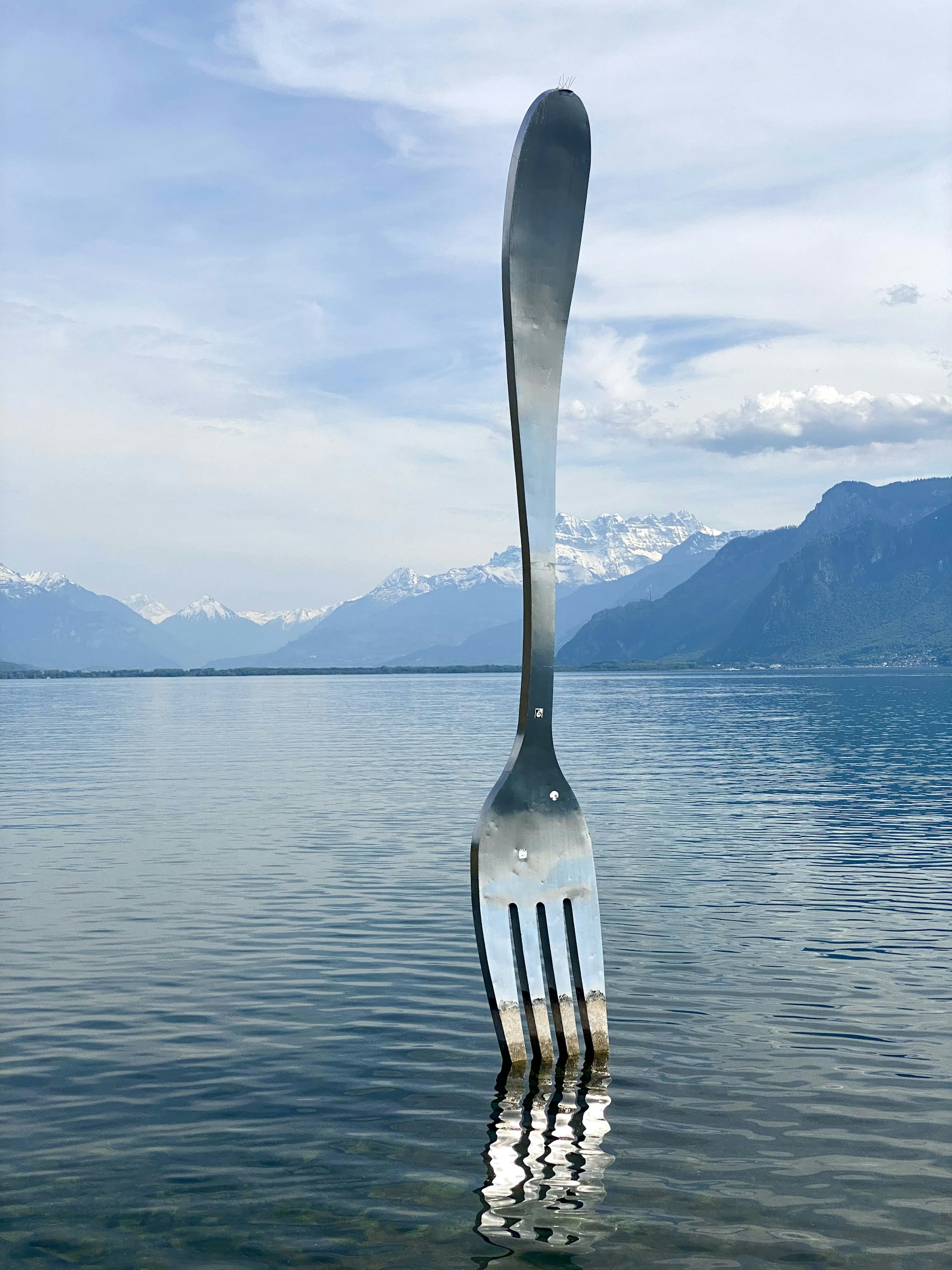 a fork sticking out of the water with mountains in the background