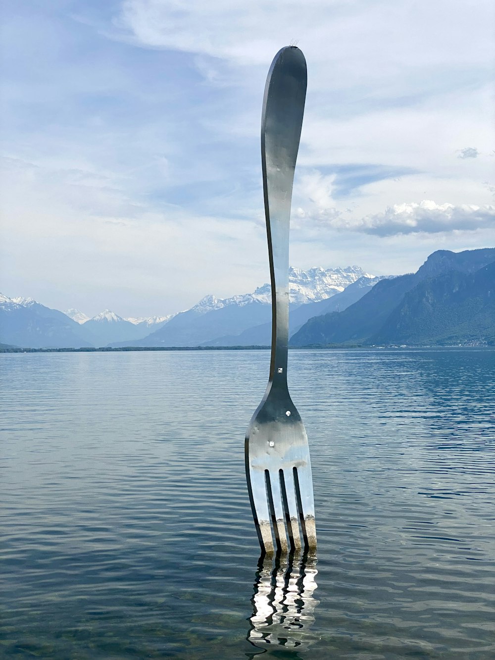 a fork sticking out of the water with mountains in the background