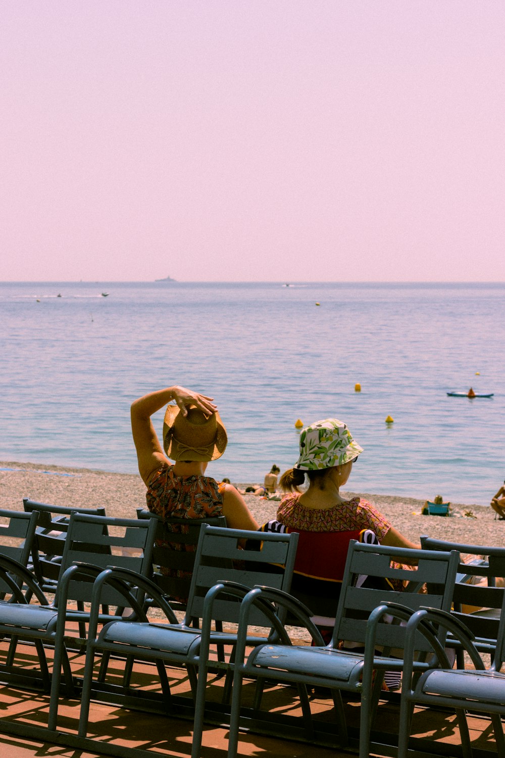 two women sitting on a bench at the beach