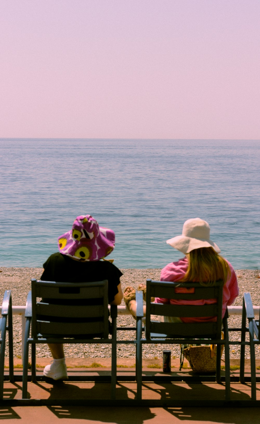 a couple of people sitting on top of a beach next to the ocean