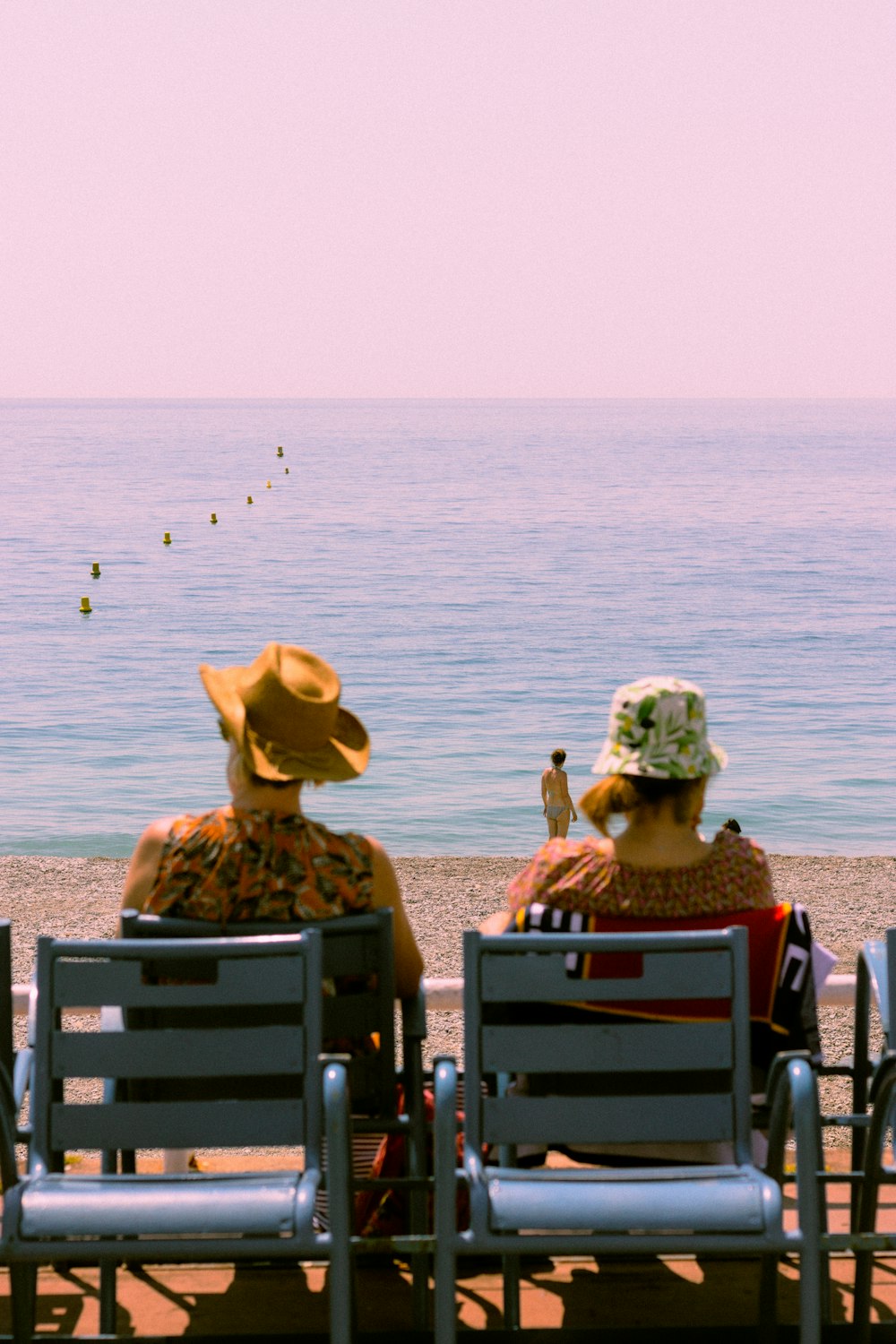 a couple of people sitting on top of a beach next to the ocean