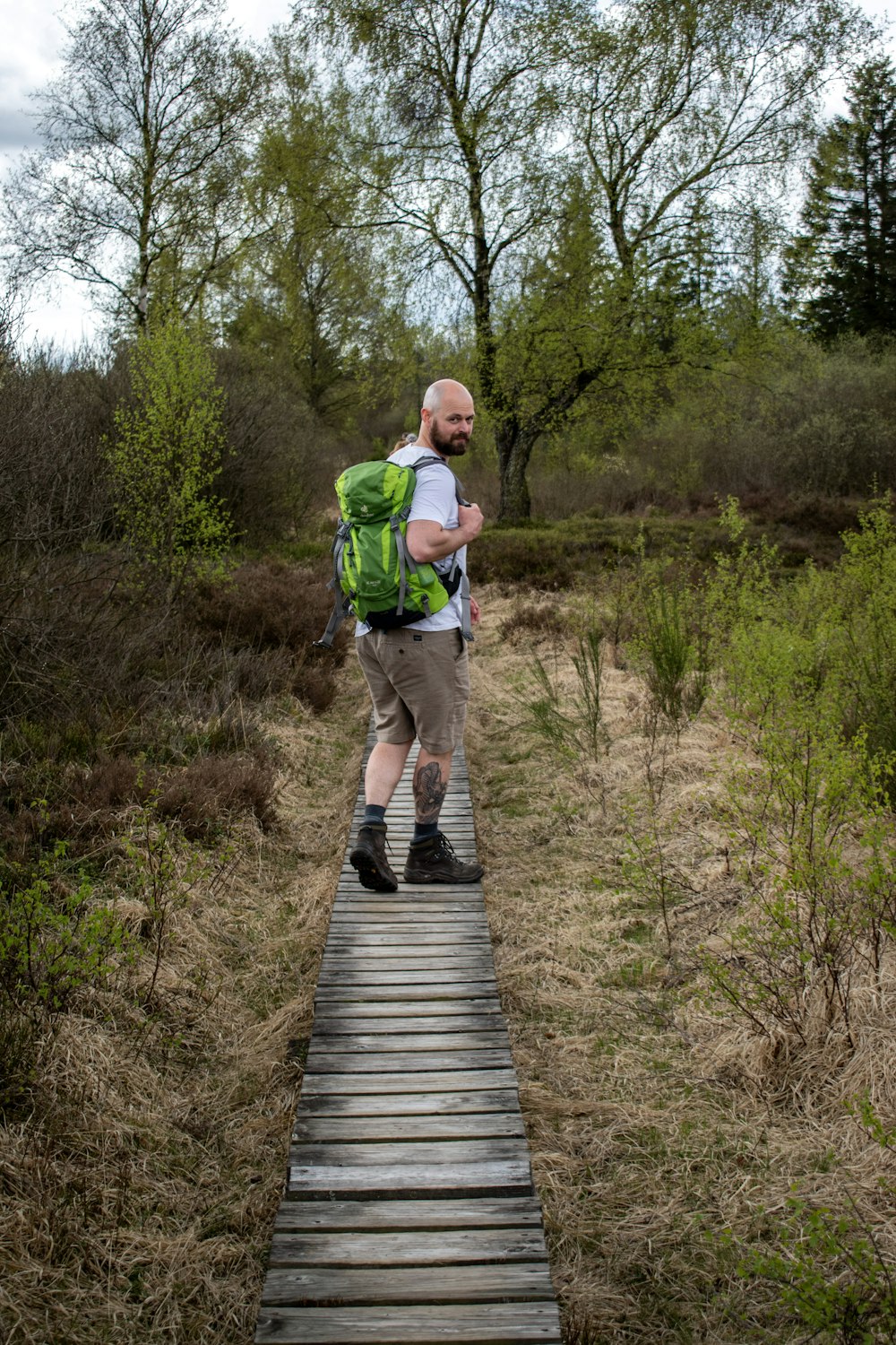 a man with a backpack walking across a wooden bridge