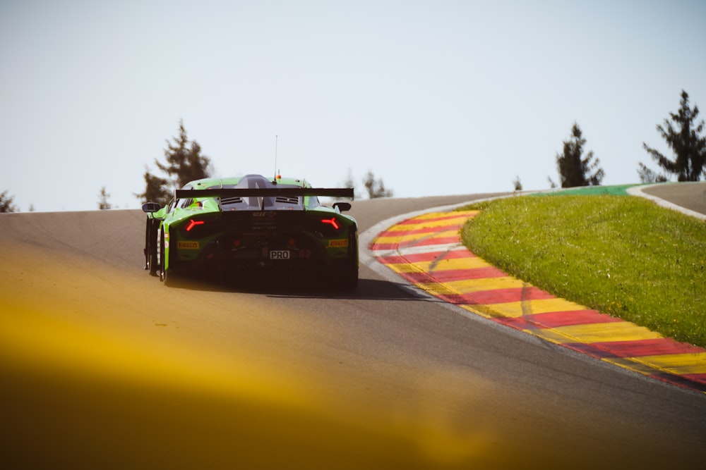 a green race car driving down a race track